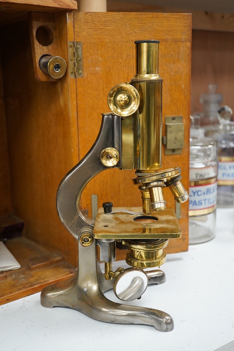 An early 20th century oak cased brass ‘Kima’ microscope by W. Watson & Sons Ltd. London, with engraved serial number under the maker’s name; 53622, with two alternative lenses in fitted compartments, microscope approxima